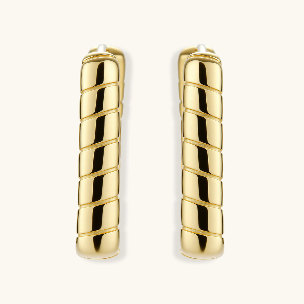 Chunky segmented gold-plated huggie hoop earrings with bamboo-inspired geometric design on white background.