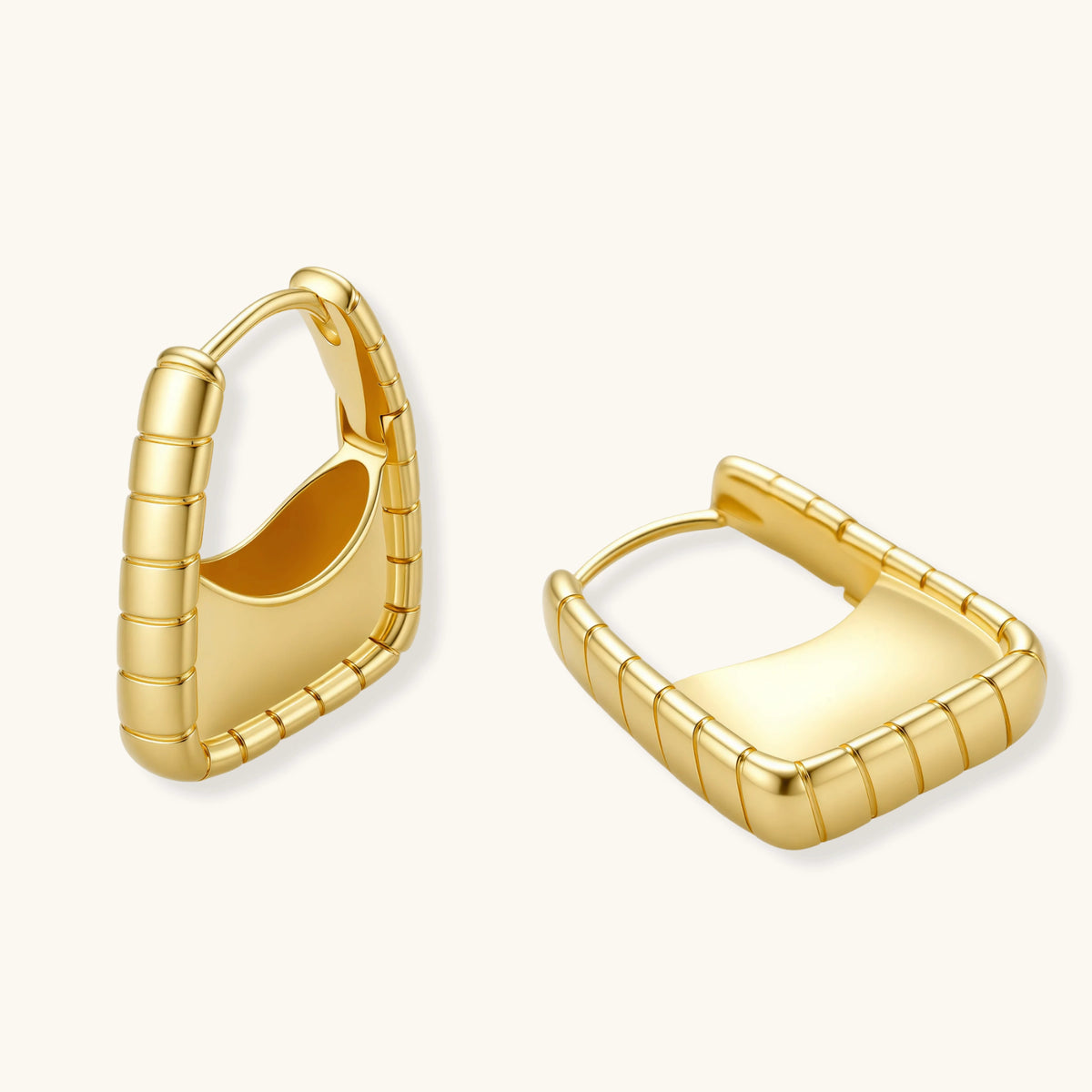 Chunky segmented gold-plated huggie hoop earrings with bamboo-inspired geometric design on white background.