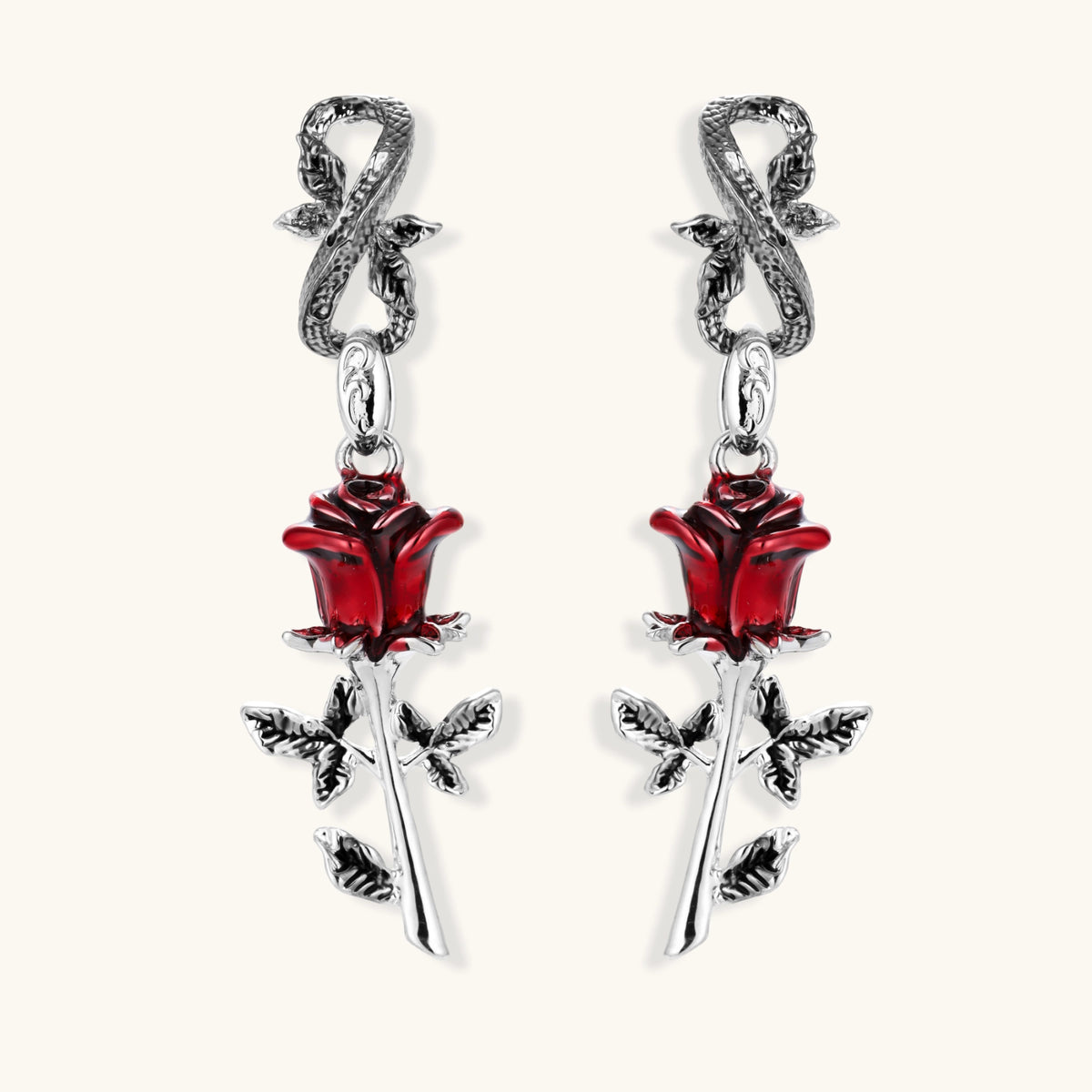 Gothic dangle earrings featuring silver serpent hooks with red enamel roses and metallic stems on white background.