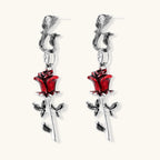 Gothic dangle earrings featuring silver serpent hooks with red enamel roses and metallic stems on white background.