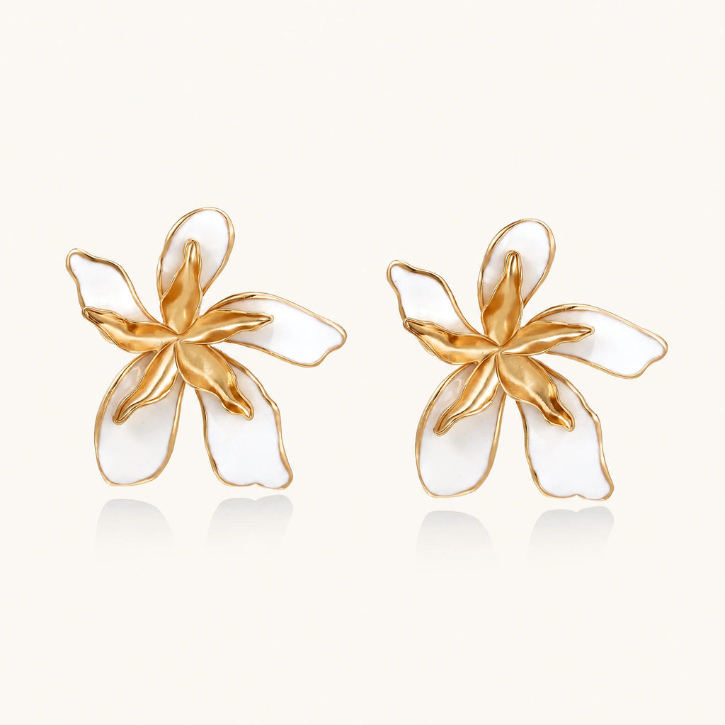 White enamel tropical flower earrings with sculptural gold-plated center and organic petal design on cream background