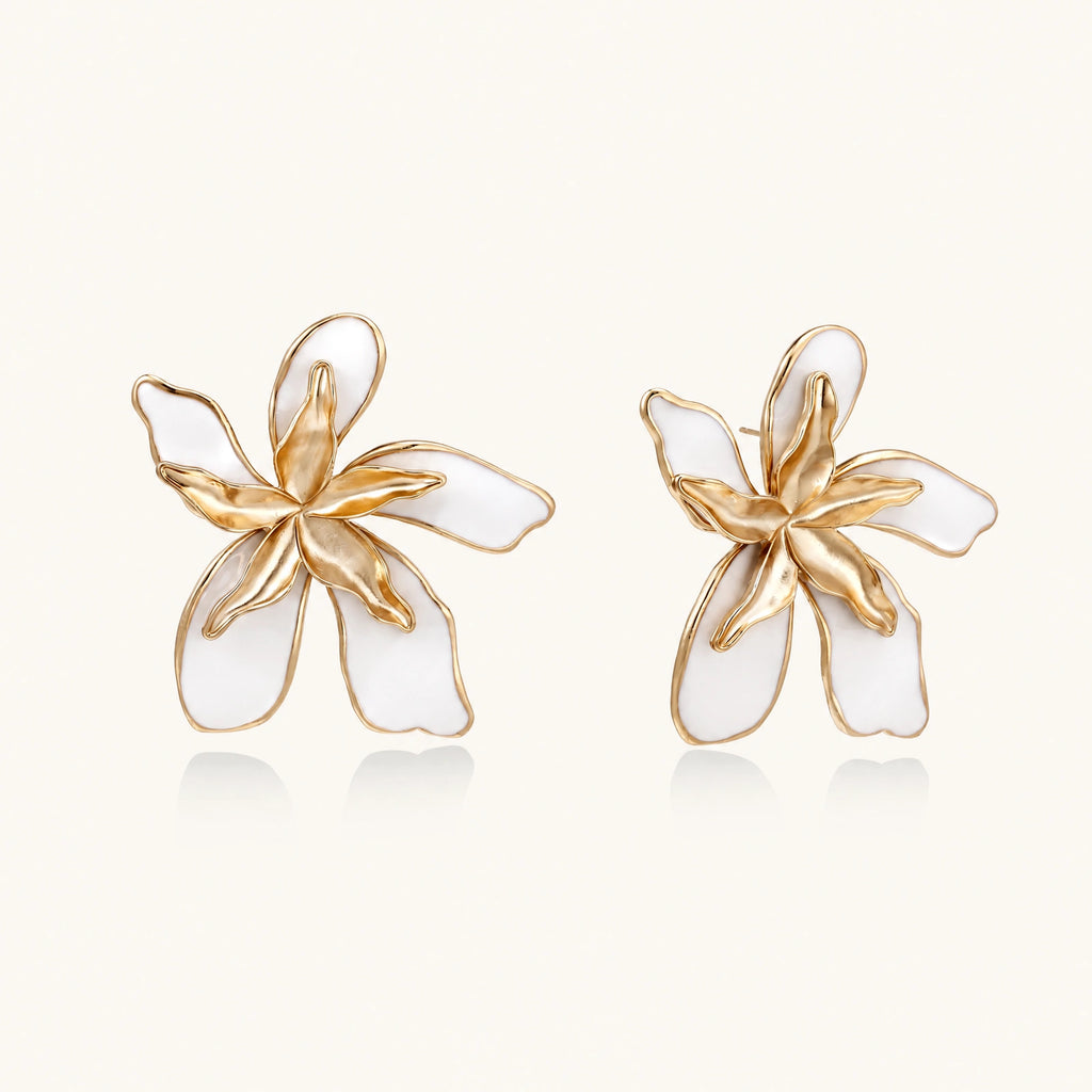 White enamel tropical flower earrings with sculptural gold-plated center and organic petal design on cream background
