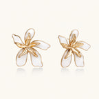 White enamel tropical flower earrings with sculptural gold-plated center and organic petal design on cream background