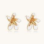 White enamel tropical flower earrings with sculptural gold-plated center and organic petal design on cream background