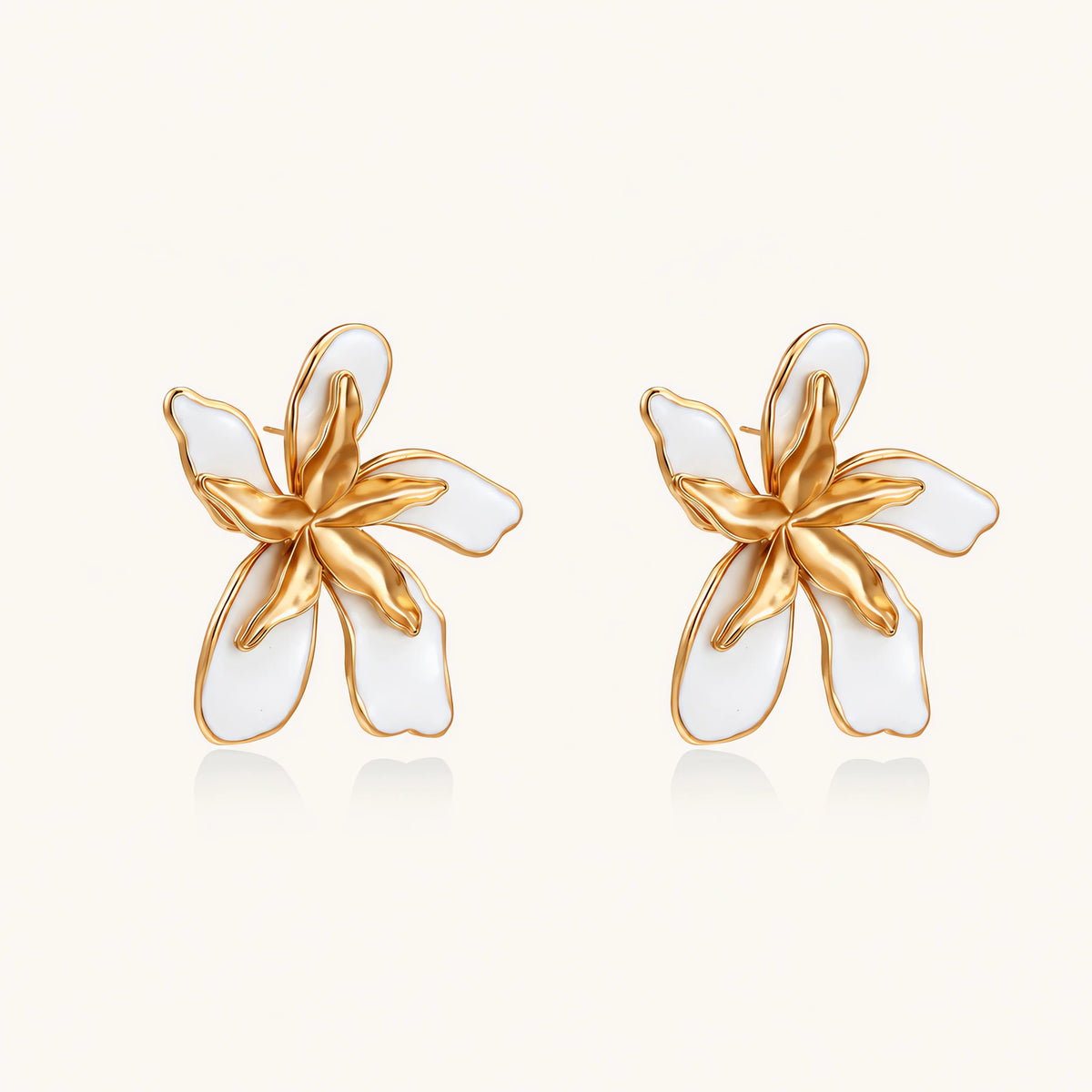 White enamel tropical flower earrings with sculptural gold-plated center and organic petal design on cream background