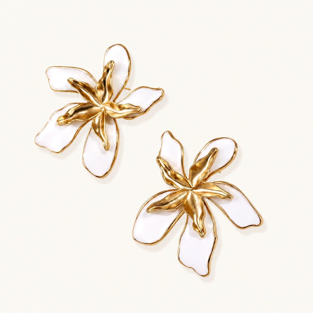White enamel tropical flower earrings with sculptural gold-plated center and organic petal design on cream background