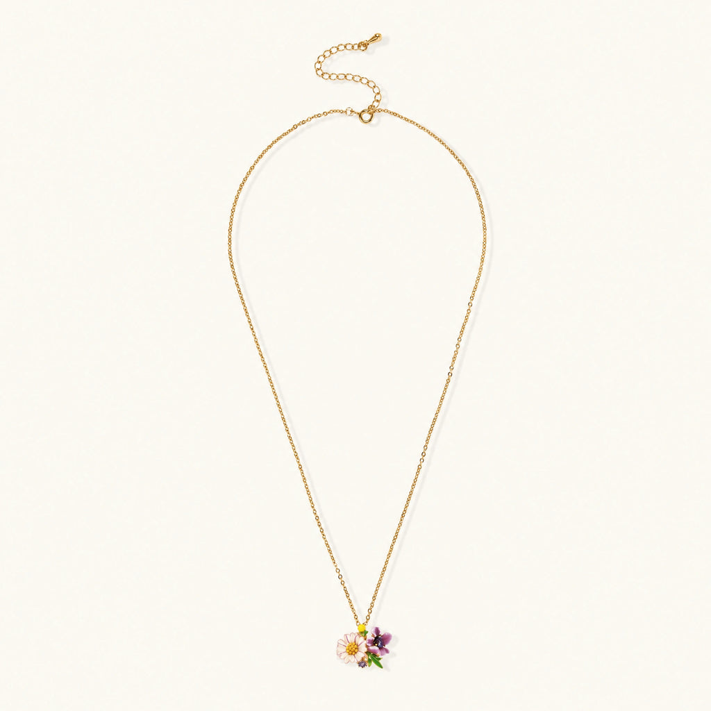 Gold-plated necklace with pink and purple enamel flower pendant featuring crystal accents on cream background