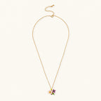 Gold-plated necklace with pink and purple enamel flower pendant featuring crystal accents on cream background