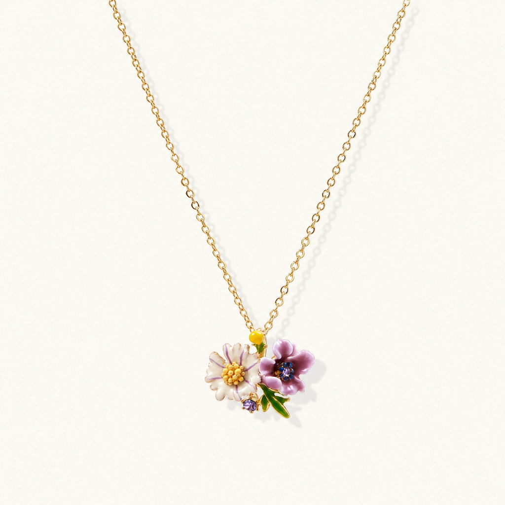 Gold-plated necklace with pink and purple enamel flower pendant featuring crystal accents on cream background