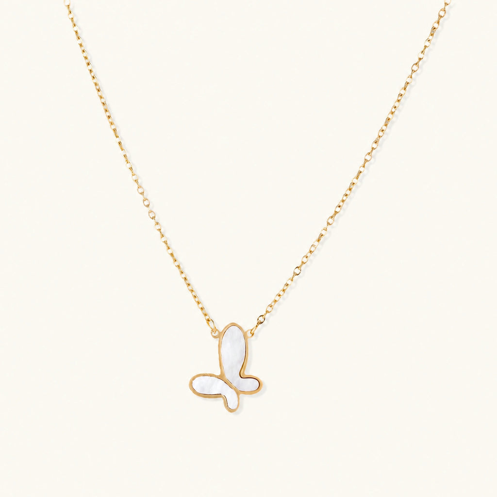 Gold-plated butterfly pendant with iridescent mother of pearl inlay on delicate chain against cream background.