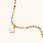 18K gold-plated oval bead bracelet with a four-leaf clover charm in mother-of-pearl or black enamel, adjustable lobster clasp, on white background.