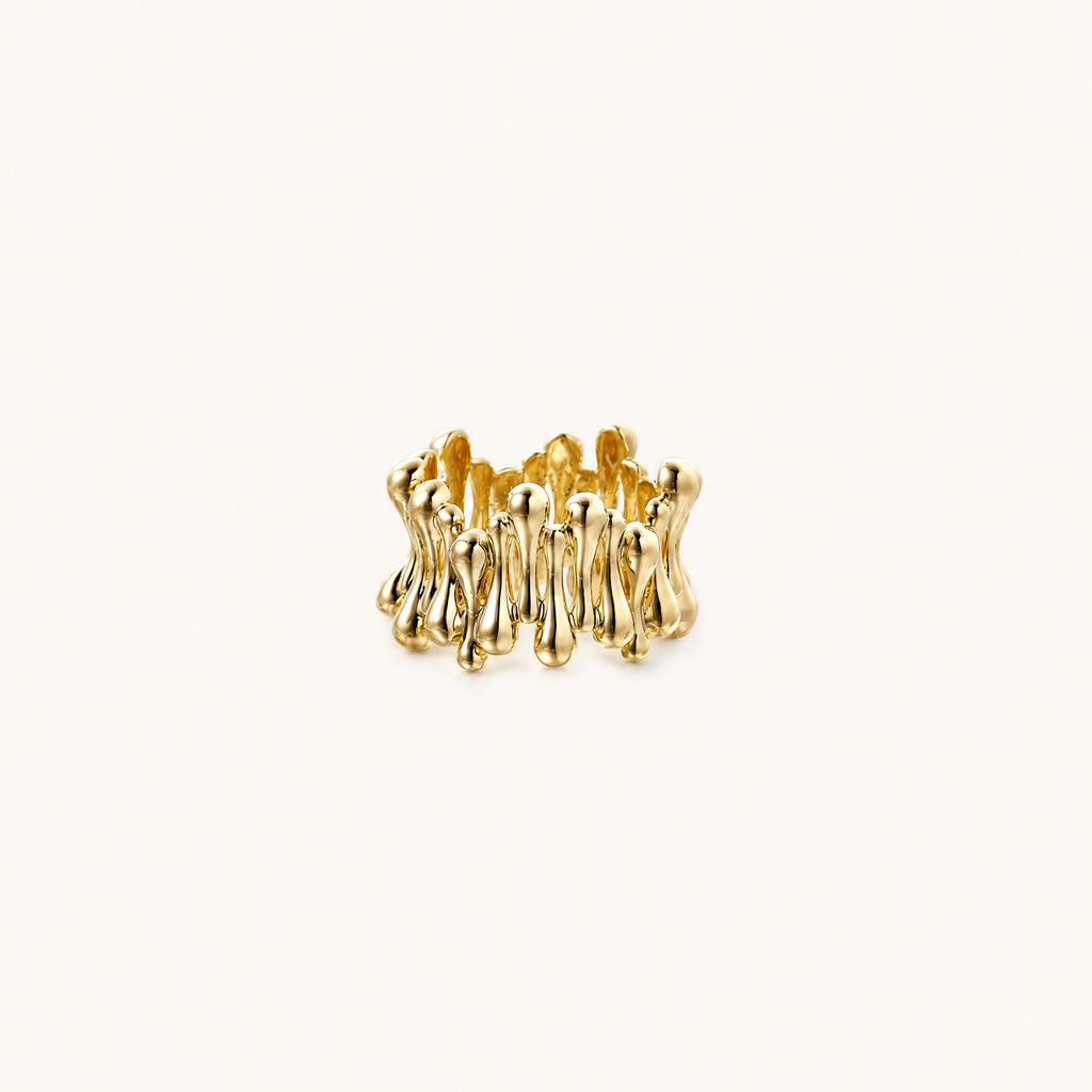 Gold-plated brass ring with sculptural petal-like elements in a wide band design on beige background