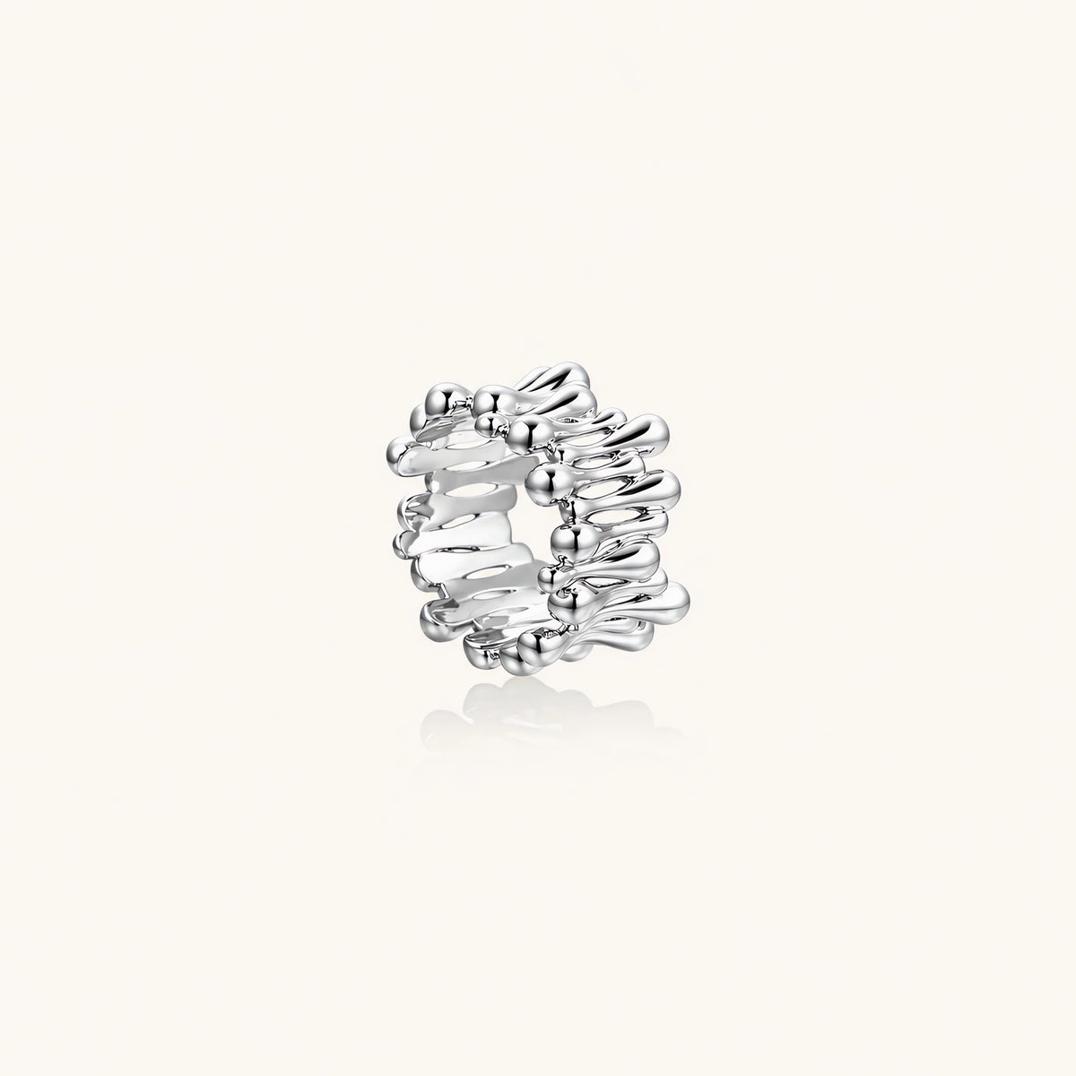 Wide band ring with sculptural wave ripples in polished white gold plated eco-brass on cream background