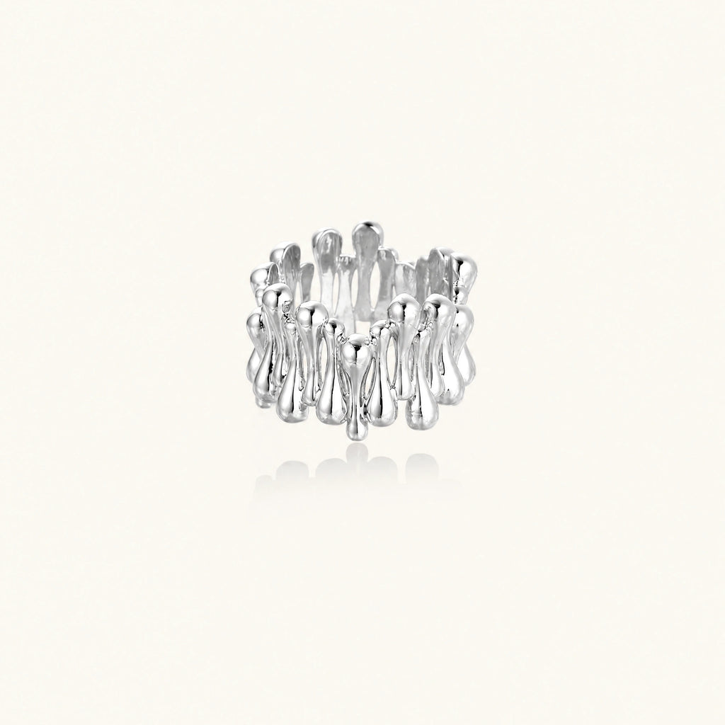 Wide band ring with sculptural wave ripples in polished white gold plated eco-brass on cream background