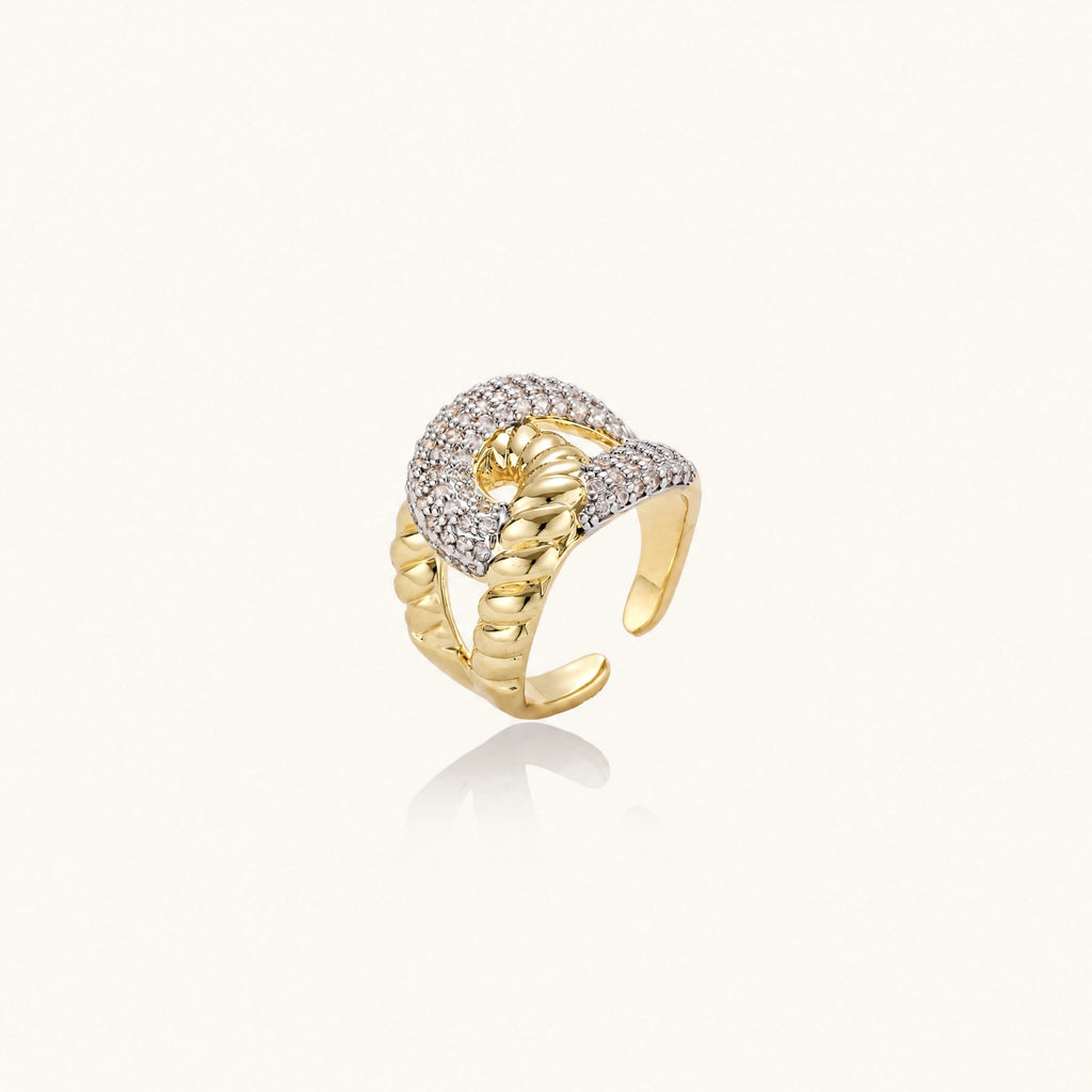 Chunky gold-plated chain-link ring with curved segments and sparkling zirconia crystals on neutral background